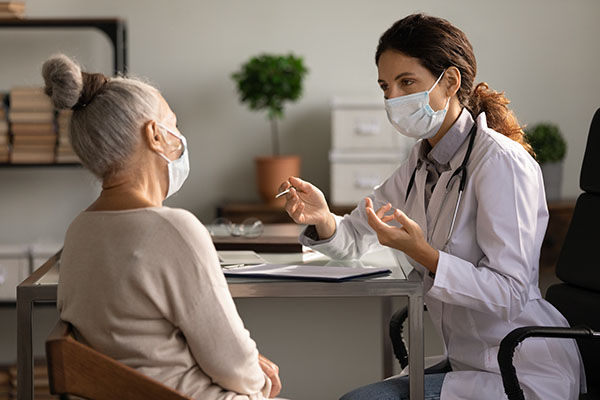Close up serious doctor wearing mask consulting mature woman patient